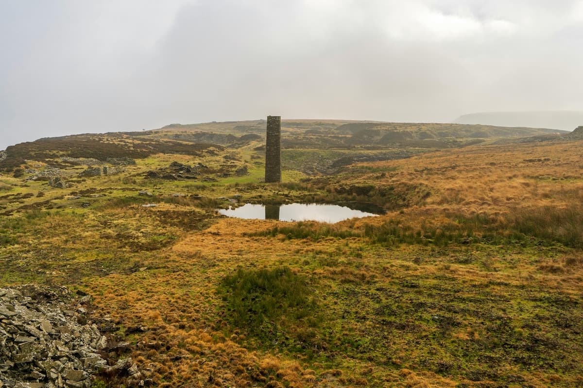 Peatland grass covered moor with small pool of water and stone tower